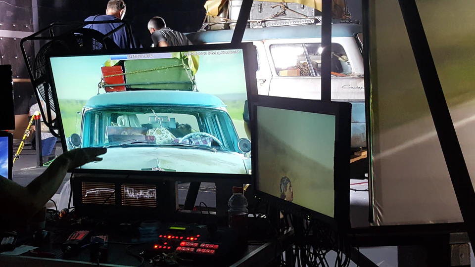 Production monitors showing the station wagon and its projected road background on The Glass Castle set.